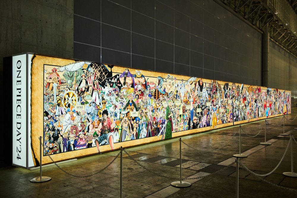 the long One Piece artwork banner in the exhibition hall, featuring many One Piece characters viewed from an angle to show its length. 