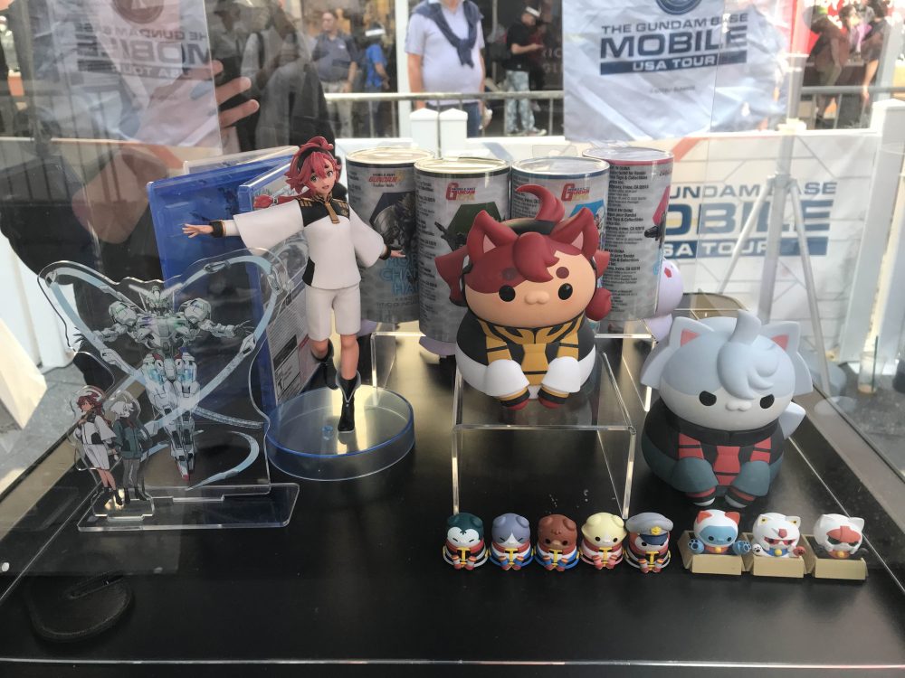 Acrylic standing statues of Zuleta Mercury and Miolin, with cat-shaped statues of Zuleta and Miolin next to their caliber, available on the Gundam Base Mobile Tour.