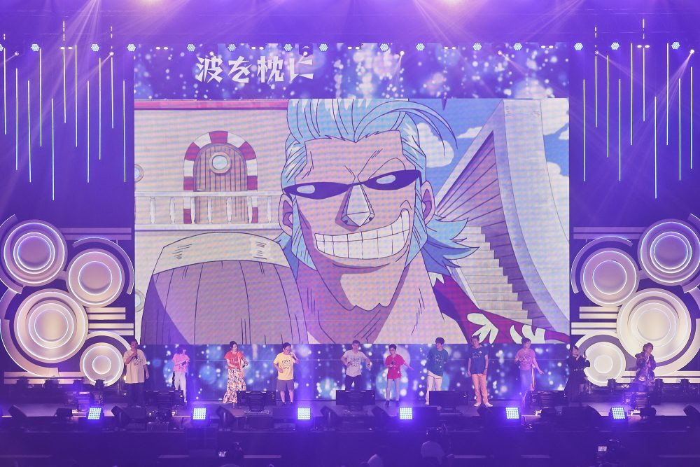 the straw hat voice actors on stage telling the crowd to say Franky's iconic line during One Piece Day.