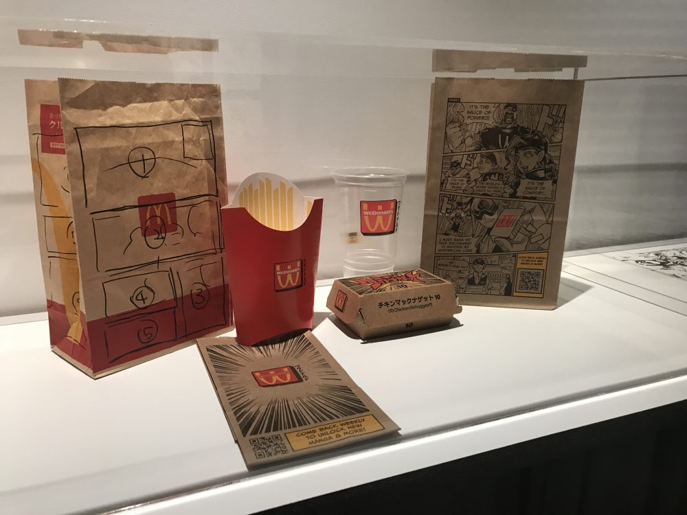 The original McDonald's paper bag on the left was used to plan where the comic panels would be placed, while the final version of Acky Bright on the right features the printed mini-comic.